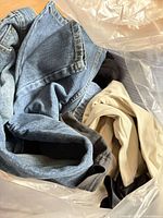 Bag containing blue denim jeans, khaki and dark trousers