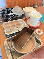 Overall view of stacked baking pans, plastic bowls, strainer and cookie cutter tin