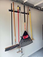 Eight yard tools hanging on wall rack showing heads and handles