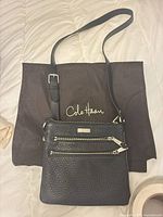 Full view of black pebbled leather crossbody with strap and dust bag