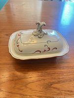 butter dish with lid showing pink scroll decoration and finial