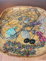 Overview of wicker tray with necklaces, brooch, pendants, bead clusters