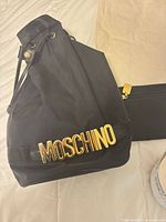 Front view of Moschino nylon backpack with gold logo letters