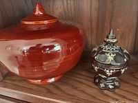 Large red glazed jar and smaller burgundy gold-decorated jar side by side