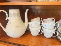 Teapot and six cups displaying pattern and overall design