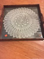 Top view of tray showing wood frame, glass top, and crocheted doily underneath