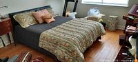 Full view of bed with headboard, comforter, pillows and surrounding items