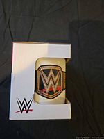 Front of boxed WWE mug showing belt graphic through window