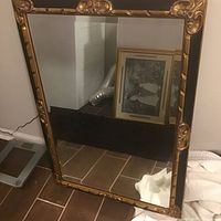 Full view of rectangular mirror with gilt-decorated black frame