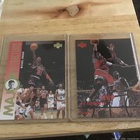 Both Michael Jordan trading cards in protective sleeves on tabletop