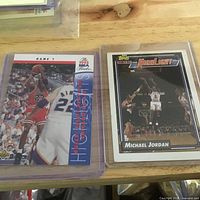 Two Michael Jordan cards in sleeves side by side on table