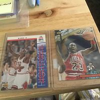 Both Michael Jordan Upper Deck cards in sleeves side by side