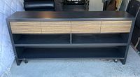 Front view of black media console with four veneer drawers and open shelves