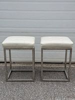 Front view of two matching off-white leather bar stools with chrome bases