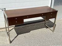 Full view of desk showing wood top, chrome legs, drawer layout