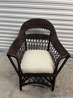 Full view of dark brown wicker rattan armchair with off-white cushion