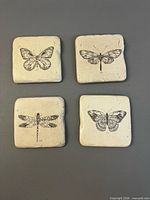Four ceramic coasters laid out showing insect illustrations