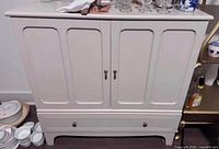 Front view of beige two-door cabinet with lower drawer