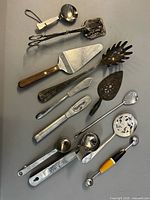 Single image showing all 12 utensils laid out on grey surface