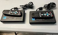 Two Digital Stream converter boxes with remotes and power cords displayed on table