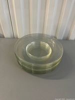 Stack of eleven clear glass plates showing concentric ring design