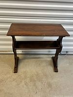 Full view of wood trestle side table showing top, legs, and lower shelf