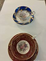 Two Paragon teacup and saucer sets in blue and red with gold decoration