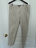 Beige and white vertical stripe Gerry Weber pants hanging on door