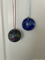 Two glass ball ornaments hanging, showing size and colour