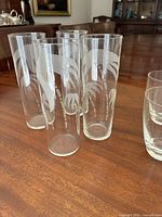 four etched tall glasses grouped on table