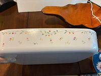 side view of white casserole dish showing floral garland pattern