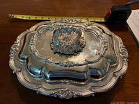 Top view of covered silver dish with tape showing length ~13 in