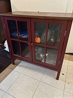 Front view showing red cabinet, glass doors, knobs, leg style