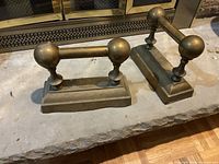 Pair of brass fireplace tool rests on hearth