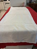 Full view of folded-out white linen tablecloth on surface showing size and overall condition