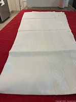 Full view of folded white linen tablecloth on red surface