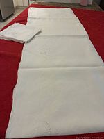 Full view of folded white linen tablecloth with napkins stacked