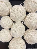 Top view of all nine cream yarn balls on black background