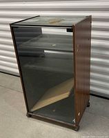 Front view of cabinet showing glass door, interior shelf, missing pins