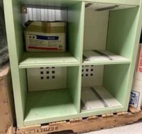 Front view of 2x2 green cube shelf showing compartments, hardware pieces and box for scale