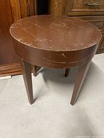 Top and side view of round brown veneer table showing scratches