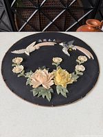 Full view of round wood plaque with carved stone birds, flowers, calligraphy