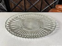 Top view of round pressed glass platter showing starburst design and scalloped rim