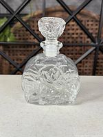 Front view of clear glass embossed perfume bottle with stopper