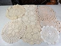 All seven crocheted cotton doilies laid out to show patterns, colors and relative sizes