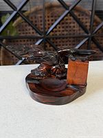 Three-quarter view showing carved eagle, ashtray bowl, pen holder block