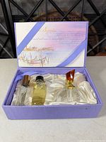 Open gift box showing three fragrance containers in satin lining