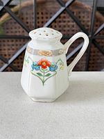 Front view of porcelain flower frog vase showing floral design and perforated top