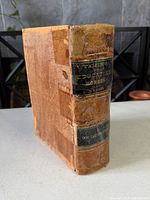 Spine and front board showing leather wear, gilt title, tape repairs