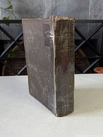 Front spine view of worn book with tape repairs